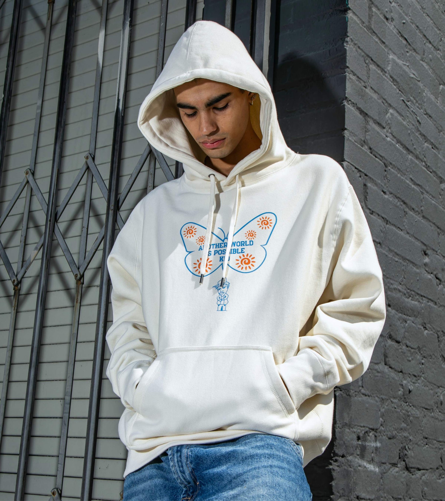 Medium-shot of male model wearing Another World Is Possible Kid bone colored heavyweight cross-grain hoodie with front print