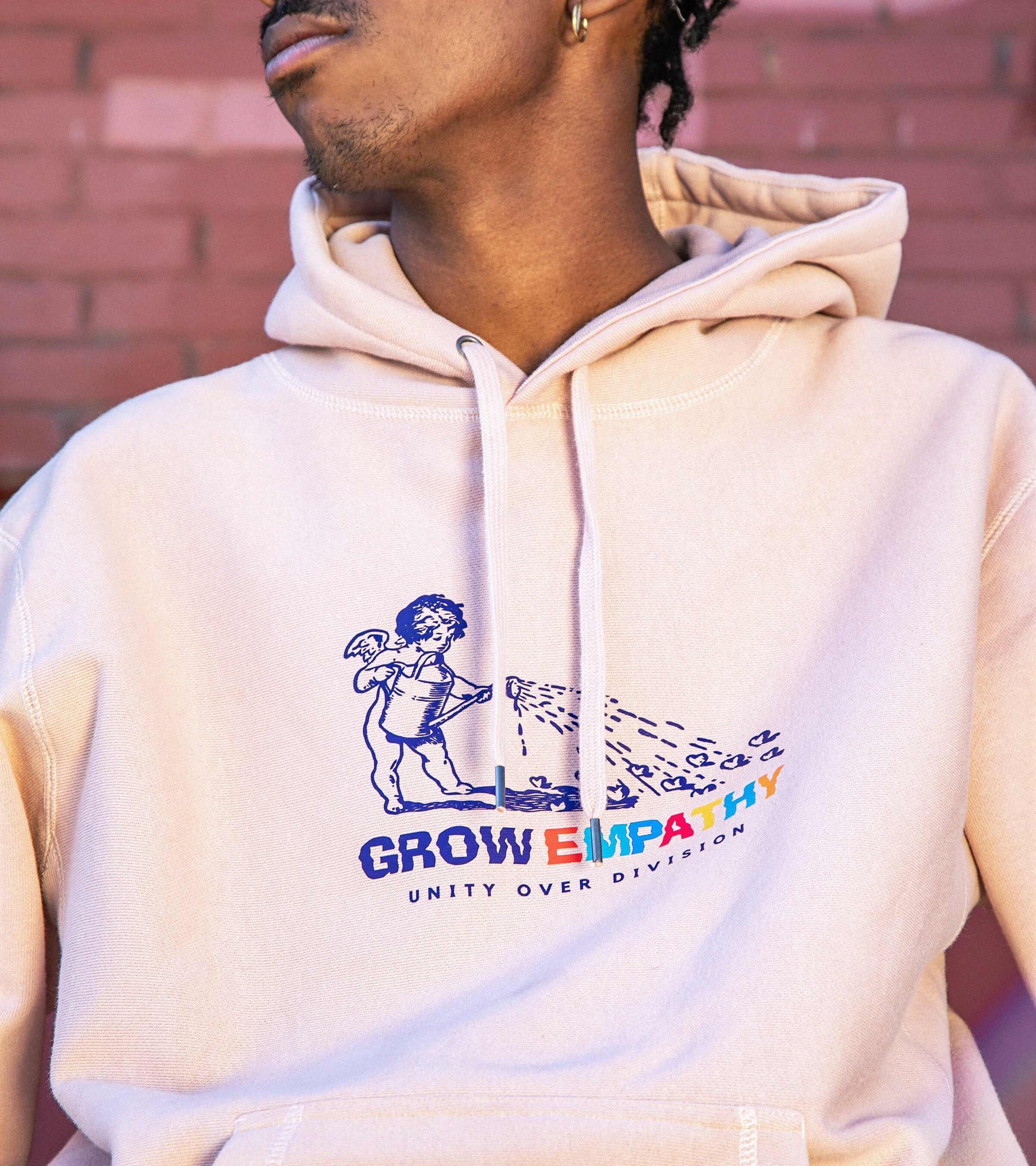 Close-up shot of graphic print with Grow Empathy Unity Over Division on dusty pink heavyweight cross-grain hoodie