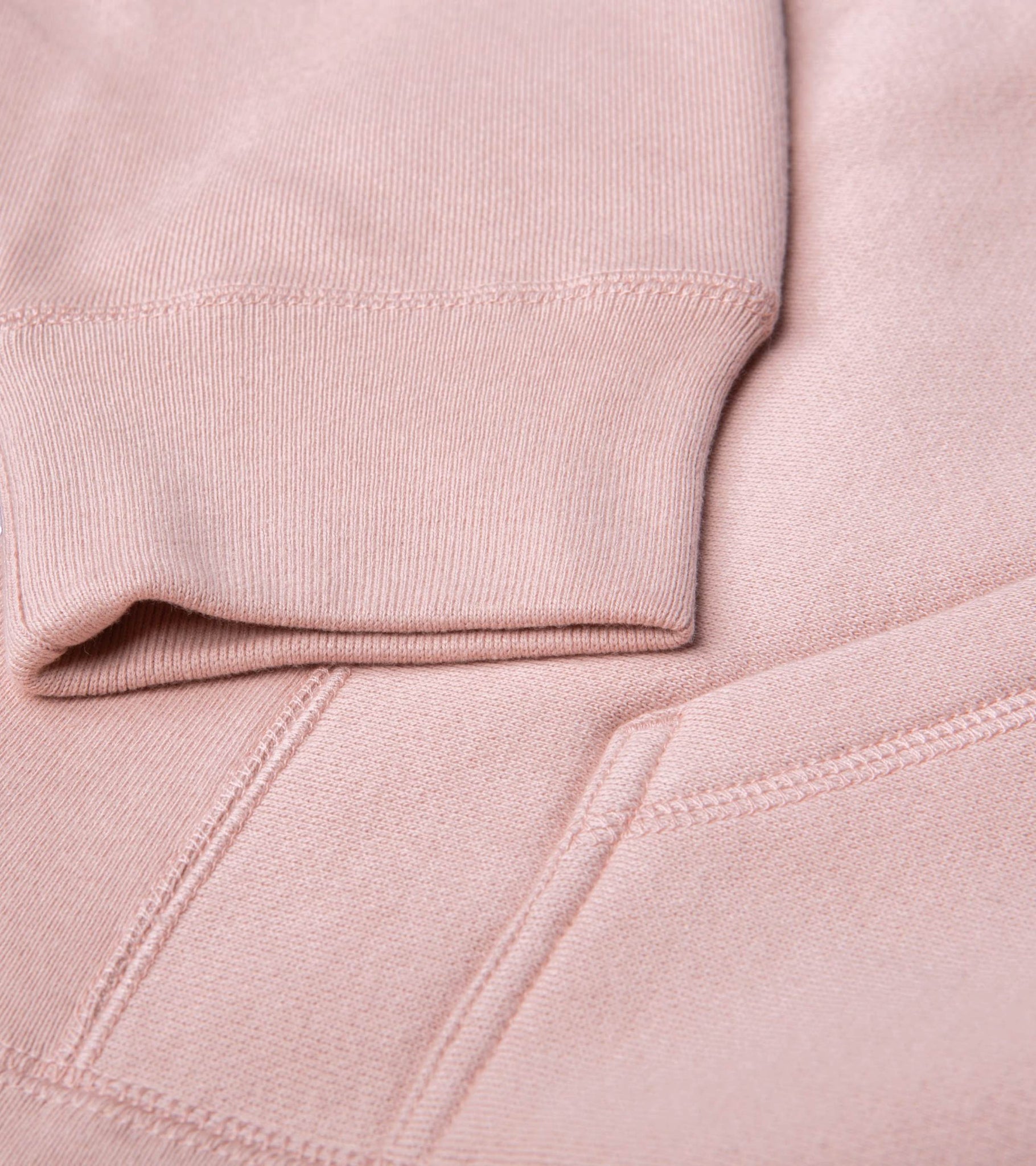 Close-up detail of ribbed sleeve cuff, cross-grain body panel and pouch seam on Grow Empathy heavyweight cross-grain hoodie in dusty pink